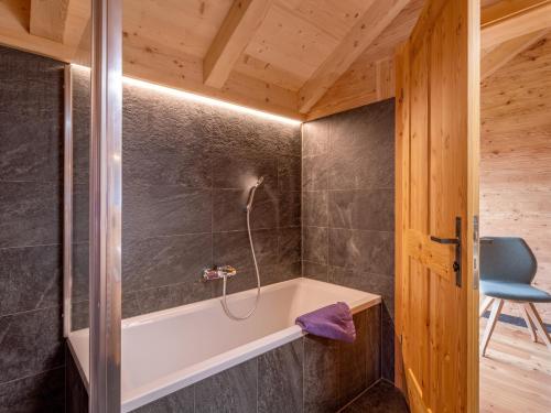 a bathroom with a tub and a chair at Refugium Dolomiten & Chalet in Sillian
