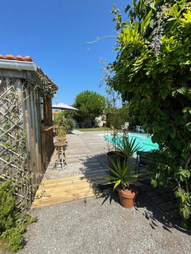 un jardin avec une allée en bois et une piscine dans l'établissement Maison de charme familiale Bassin Arcachon, à La Teste-de-Buch