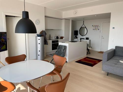 a kitchen and living room with a table and chairs at Luksuslejlighed på 7 sal med elevator, vestvendt altan og udsigt over havn og by in Copenhagen