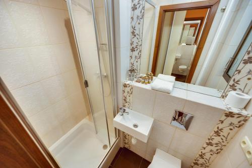 une salle de bain avec un lavabo, une douche et un miroir dans l'établissement Orange by OneApartments, à Gdańsk