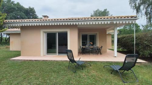 une maison avec deux chaises et une table dans la cour dans l'établissement La Villa des Pins Confort pour 6 personnes, à Andernos-les-Bains
