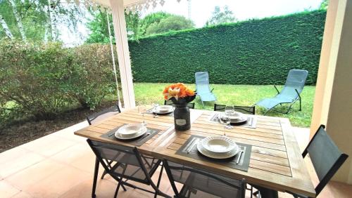 une table en bois avec des chaises et un vase de fleurs dans l'établissement La Villa des Pins Confort pour 6 personnes, à Andernos-les-Bains