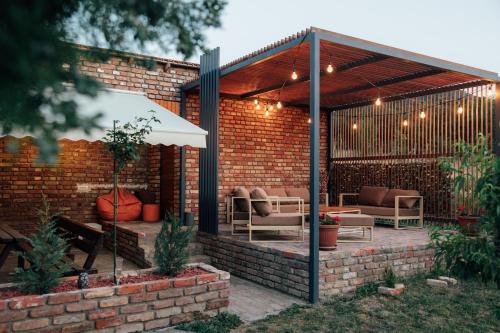 a pergola with chairs and tables on a brick wall at Šapat Vetra vikendica in Vršac