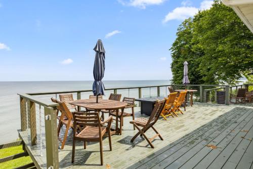 a deck with chairs and a table with an umbrella at Sunset Haven - Lakeside Retreat in GOTL in Geneva