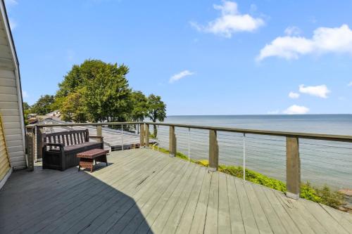 a wooden deck with a bench and the ocean at Sunset Haven - Lakeside Retreat in GOTL in Geneva