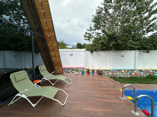 two green chairs sitting on a wooden deck at Qafqaz Suite Paradise Chalet & SPA in Gabala