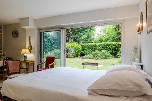 une chambre avec un grand lit et une grande fenêtre dans l'établissement Veeve - The Garden of La Muette, à Paris
