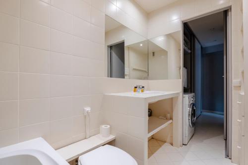 une salle de bain blanche avec un lavabo et des toilettes dans l'établissement Veeve - The Garden of La Muette, à Paris
