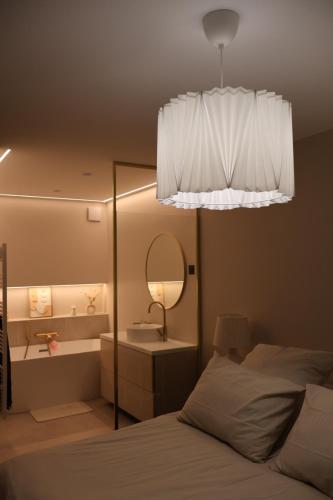 - une chambre avec un lit, un miroir et un lustre dans l'établissement Appartement vue sur seine, à Courbevoie