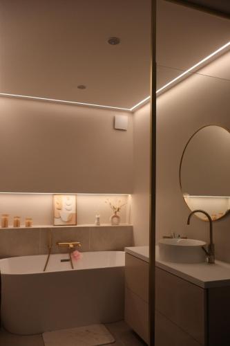 une salle de bain avec une baignoire, un lavabo et un miroir dans l'établissement Appartement vue sur seine, à Courbevoie