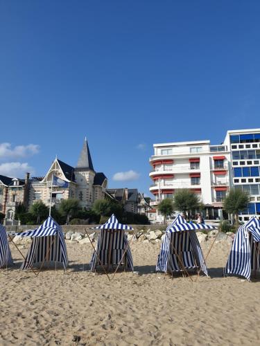 un groupe de chaises longues assises sur une plage dans l'établissement Phare Away - 20m plage - belle villa royannaise -, à Royan
