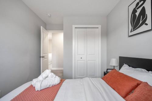 a bedroom with a large white bed with an orange blanket at Large House Near Calgary Airport with Central AC, Double Car Garage Parking, Upgrade Stay, Netflix, Sleeps 8 in Calgary