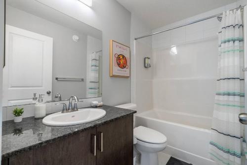 a bathroom with a sink and a toilet and a tub at Large House Near Calgary Airport with Central AC, Double Car Garage Parking, Upgrade Stay, Netflix, Sleeps 8 in Calgary