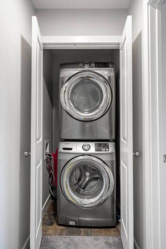 a utility room with a washer and dryer at Large House Near Calgary Airport with Central AC, Double Car Garage Parking, Upgrade Stay, Netflix, Sleeps 8 in Calgary