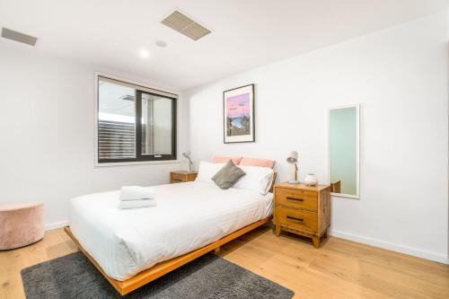 a white bedroom with a bed and a window at Exclusive Braddon 2BR APT near Civic - Hosted by Canstay in Canberra