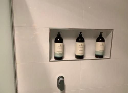 three bottles of wine sitting on a shelf in a bathroom at Warm and Spacious 5BR Home w WIFI and Multiple Parking - Hosted by Canstay in Weetangerra