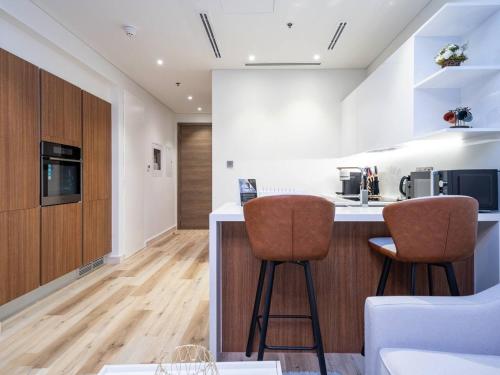 a kitchen with two bar stools and a counter top at Cosy Modern Waterfront Studio in Maritime City in Dubai