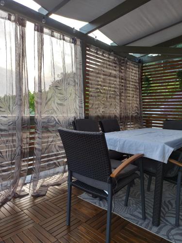 a table and chairs on a patio with curtains at NemCsuri Vendegház Somló in Somlóvásárhely