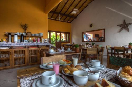 a dining room with a table with plates of food at Pousada Maria Pitanga in Arraial d'Ajuda