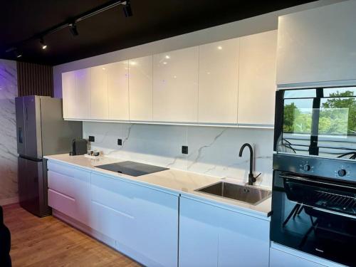 une cuisine avec des armoires blanches, un évier et une cuisinière dans l'établissement Penthouse Manhattan jacuzzi balneo suite luxe, à Toulouse