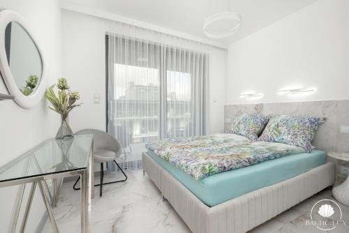 a bedroom with a bed and a table and a mirror at Baltic Lux Pogorzelica II in Pogorzelica