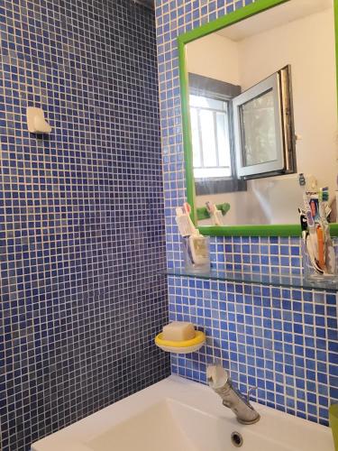 La salle de bains est pourvue de carrelage bleu, d'un lavabo et d'un miroir. dans l'établissement Le Loft 3, à Montpellier