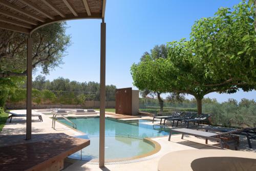 a swimming pool with benches and tables and trees at TheTree Villa, with Heated Pool & Spa Whirlpool in Gállos