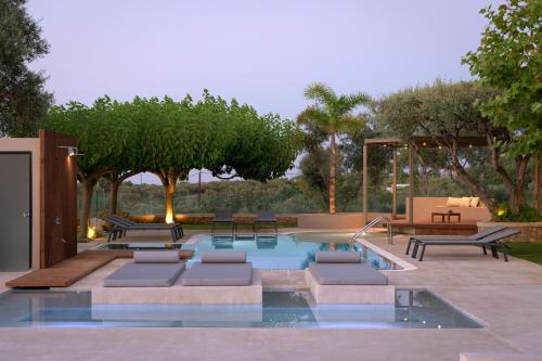 a swimming pool with benches and tables and trees at TheTree Villa, with Heated Pool & Spa Whirlpool in Gállos
