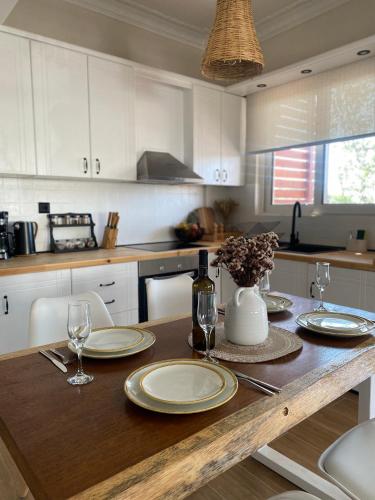 a kitchen with a wooden table with plates and wine glasses at Bohemian Paradise Villa in Paradeísion