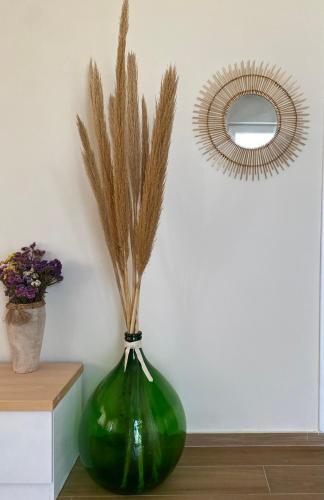 a green vase with dry grass in it next to a mirror at Bohemian Paradise Villa in Paradeísion