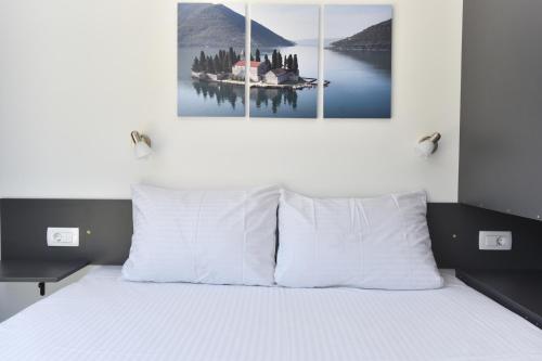 a bedroom with a bed with two paintings on the wall at Apartments Jadranski Biser in Čanj