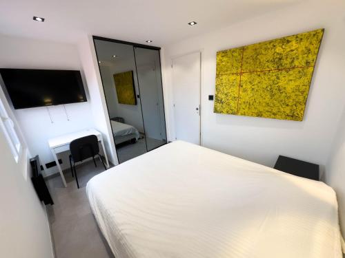 a bedroom with a white bed and a yellow painting on the wall at Luxueux haut de villa 4 per à 30m de la plage in Sainte-Maxime