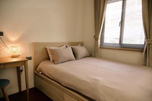 a small bedroom with a bed with a window at Qingyu B&B in Luzhu