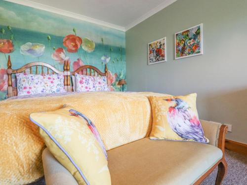a bedroom with a bed with a couch and a painting at Hazel's Cottage in Campbeltown