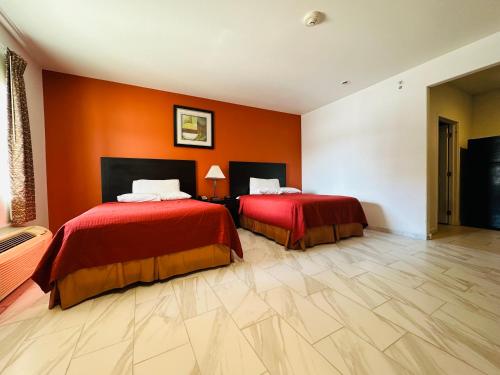 two beds in a room with orange walls at Lux Inn and Suites in Three Rivers