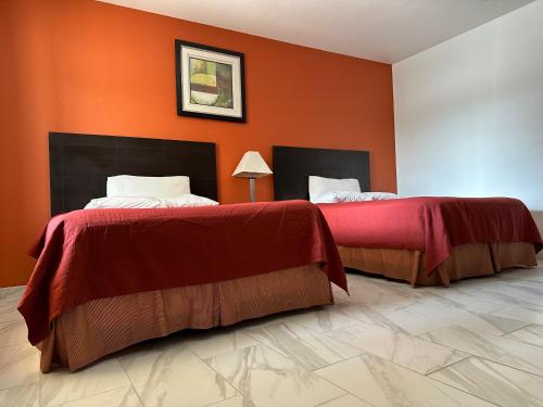 two beds in a room with orange walls at Lux Inn and Suites in Three Rivers