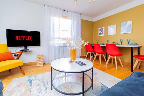a living room with a tv and red chairs at Air Maison - Driftwood Apartment in Portsmouth