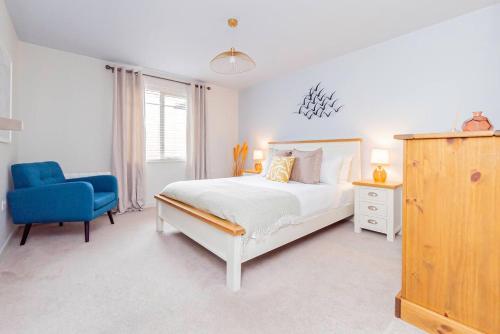 a white bedroom with a bed and a blue chair at Air Maison - Driftwood Apartment in Portsmouth