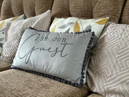 a pillow that says be our guest on a couch at Martha's Cottage in Donaghcloney