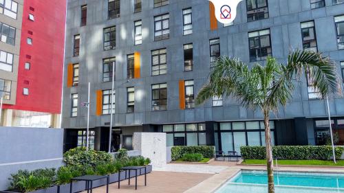 a building with a palm tree in front of it at Nuevo Dpt l Alberca + Padel l Soumaya 10 min in Mexico City
