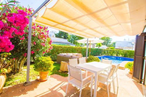 a patio with a white table and chairs and flowers at Beautiful villa near the beach in Port de Pollensa