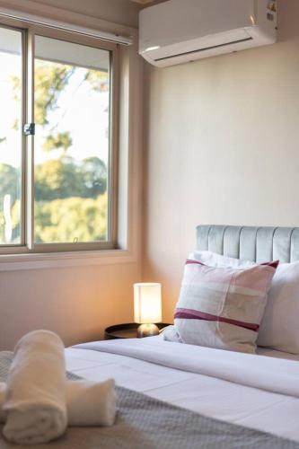 a bedroom with a bed with a window and a pillow at Spacious 3 bed Retreat 1min to Mall Sunnybank Hill in Brisbane