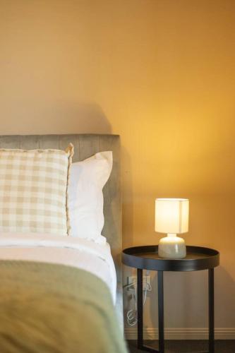 a bed with a table with a lamp on it at Spacious 3 bed Retreat 1min to Mall Sunnybank Hill in Brisbane