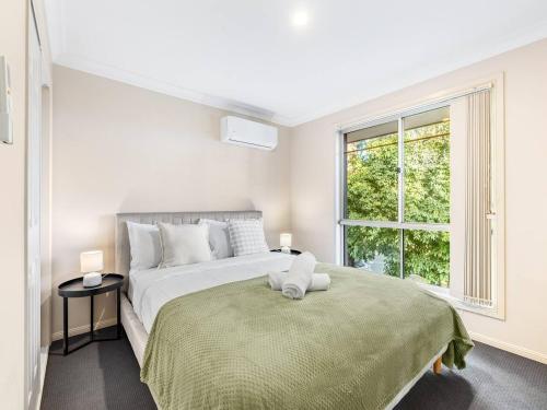 a white bedroom with a large bed and a window at Spacious 3 bed Retreat 1min to Mall Sunnybank Hill in Brisbane