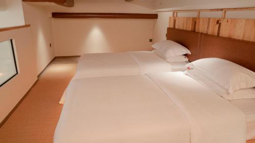 two beds in a room with white sheets and pillows at Patio Spring Holiday Inn -- Free round trip pick-up service --Panoramic view of Tianmen Mount in Zhangjiajie