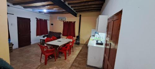 a kitchen and dining room with a table and red chairs at Hospedaje Catalina in Belén
