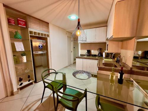 a kitchen with a glass table and green chairs at Landscape Beira Mar - Lindo, Luxo, Frente mar in Fortaleza