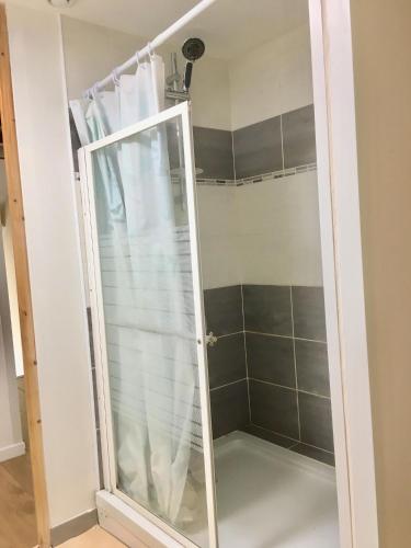une douche avec une porte vitrée dans une salle de bain dans l'établissement Grande chambre - fumeur, à Dunkerque