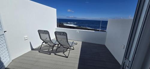 two chairs sitting on a balcony overlooking the ocean at Inside The Sea in Lagoa
