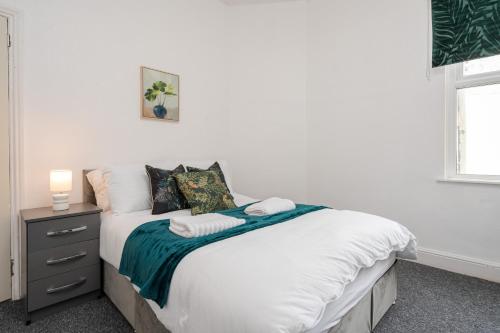 a bedroom with a bed with white sheets and a nightstand at Entire 5 Bedroom home in Birkenhead-Free Parking, Group & Family-Friendly, Free Internet in Birkenhead